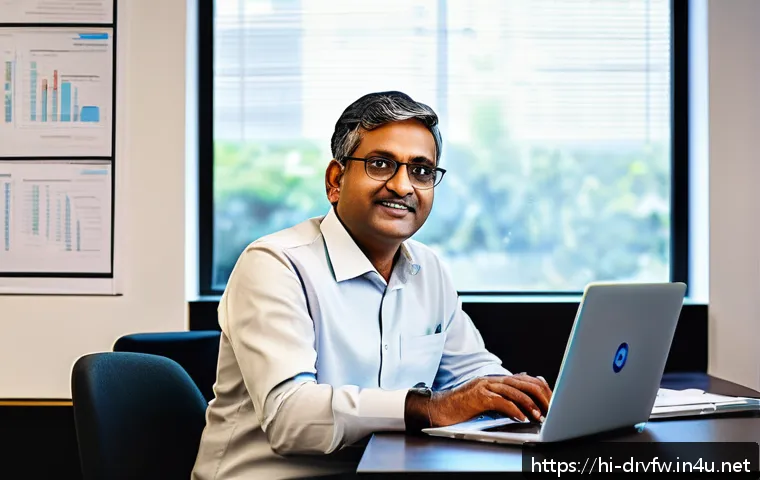 드라이버 백업 및 복구 가이드 - A professional workspace scene showing a middle-aged Indian man wearing casual office clothes, sitti...